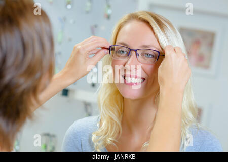 Femme essayant sur des verres en magasin optique Banque D'Images