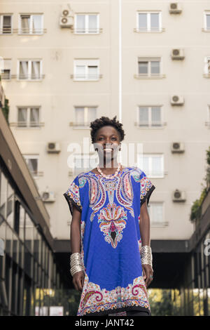 L'un, jeune adulte, black african american woman, 29 ans, gai, heureux coup du haut du corps, zone urbaine, de la construction, à la recherche d'appareil photo, low angle view, Banque D'Images