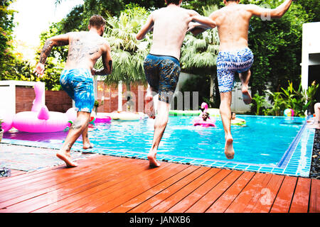 Groupe d'hommes divers sauter à la piscine Banque D'Images