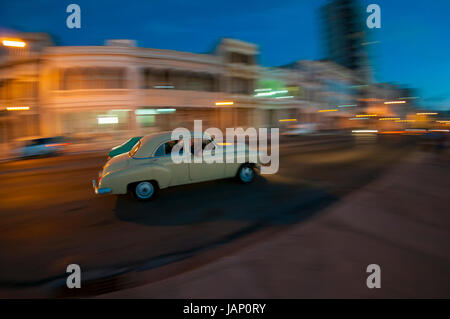 Vintage voiture américaine servant de taxi passe dans un flou le long du Malecon, dans le centre de La Havane au crépuscule. La technique de déplacement, vitesse d'obturation lente. Banque D'Images