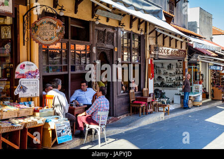 Homme grec s'asseoir à l'extérieur d'un chat café sur la rue 177, Sygrou, la vieille ville de Rhodes, Rhodes, Grèce Banque D'Images