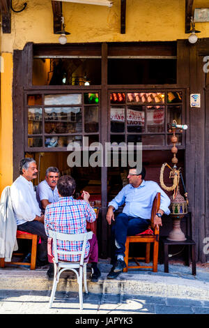 Homme grec s'asseoir à l'extérieur d'un chat café sur la rue 177, Sygrou, la vieille ville de Rhodes, Rhodes, Grèce Banque D'Images