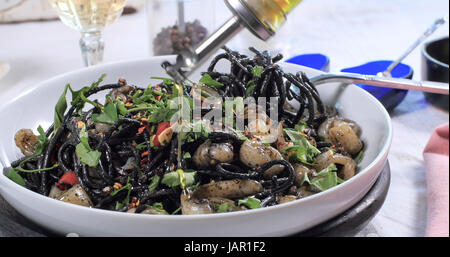 Verser l'huile d'olive sur les pâtes aux calamars (noir) et de l'encre de seiche Banque D'Images
