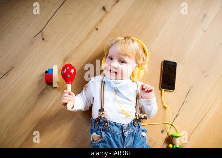 Petit garçon avec des écouteurs, l'écoute de la musique, jouant d'un jouet Banque D'Images