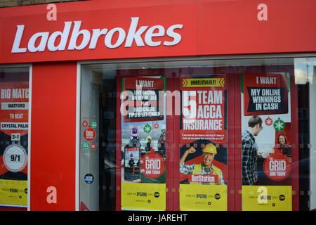 Ladbrokes Bookmakers football pignon de jeu de signe de joueur à l'extérieur de la fenêtre du magasin affiche d'entrée affiches style de vie gagner de l'argent perdu en espèces Banque D'Images