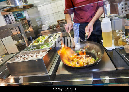 Cuisiner dans une cuisine commerciale est flambeing dans une poêle Banque D'Images