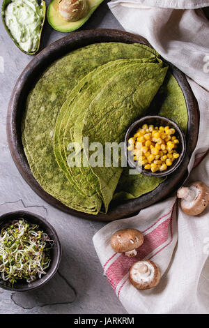 Tortilla d'épinards vert matcha ingrédients vegan pour le remplissage. Maïs doux, avocat, paprika vert, les germes, les champignons servi dans la plaque en terre cuite ov Banque D'Images