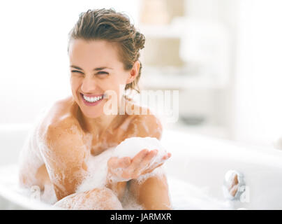 Portrait of happy young woman playing avec mousse dans la baignoire Banque D'Images