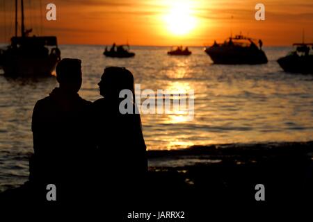 Un jeune couple dans l'amour qui se profile par le coucher de soleil sur Sunset Strip, Ibiza, Espagne Banque D'Images