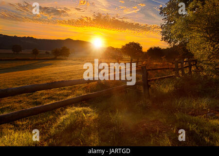 Lever de soleil au-dessus de haarstrang, brillant dans moehnetal brumeux, clôture en premier plan, emplacement : warstein-belecke, Sauerland, Allemagne ; voir même les images HDR de l'emplacement, Banque D'Images