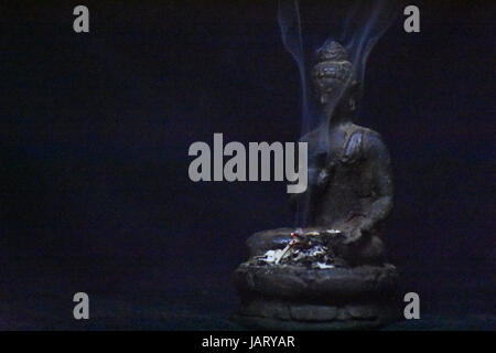 Statue de Bouddha avec de la fumée d'encens sur un arrière-plan sombre tourbillonnant suggèrent la paix et le calme. Banque D'Images