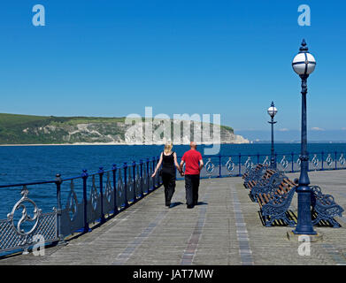 Couple en train de marcher le long de la jetée, le regard vers la mer, Swanage, Dorset, Angleterre, Royaume-Uni Banque D'Images