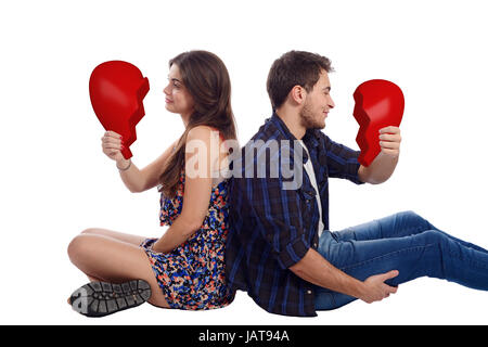 Portrait of a young couple holding deux moitiés de cœur brisé. Isolé sur fond blanc. Banque D'Images