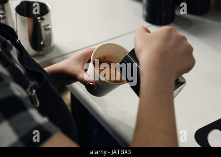 Barista verse la crème dans la tasse de café au café. Photo horizontale Banque D'Images