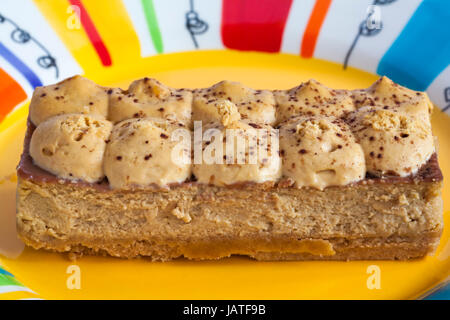 M&S Banoffee cheesecake tranche sur la plaque de couleur Banque D'Images