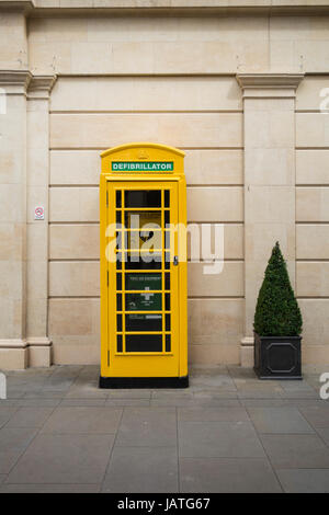 Un défibrillateur électrique automatique, plus l'équipement de premiers soins et téléphone installé dans une cabine téléphonique jaune, Southgate Bâtiment de direction, Bath, Royaume-Uni Banque D'Images