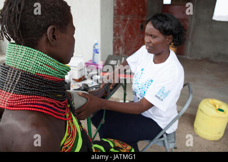 Une infirmière en santé communautaire prend une femme de la pression artérielle, les zones rurales du Kenya, Afrique Banque D'Images