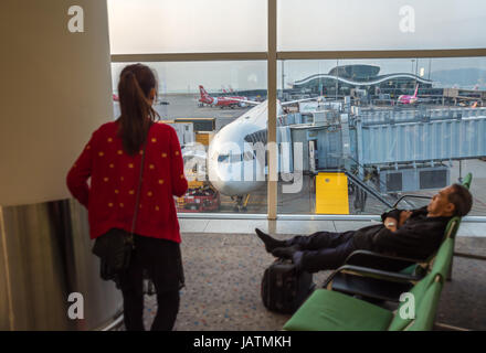 Hong Kong, Chine, le 28 février 2015. deux passagers attendant leur vol avec un avion à l'arrière-plan Banque D'Images