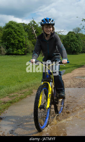 Boy riding bike par flaque Banque D'Images
