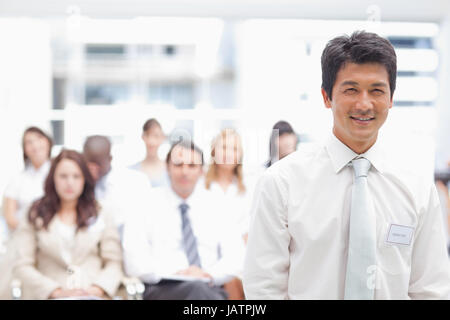 Businessman smiling tandis qu'il se trouve en face de ses collègues Banque D'Images