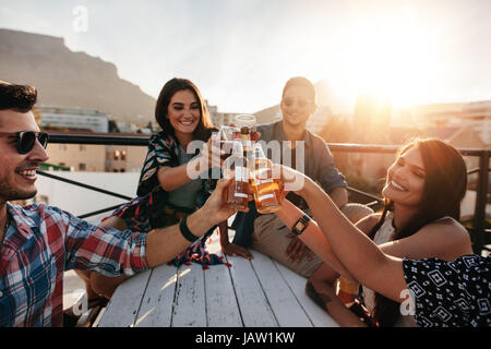 Friends toasting drinks at a party. Young Friends hanging out at rooftop party et profiter de boissons. Banque D'Images