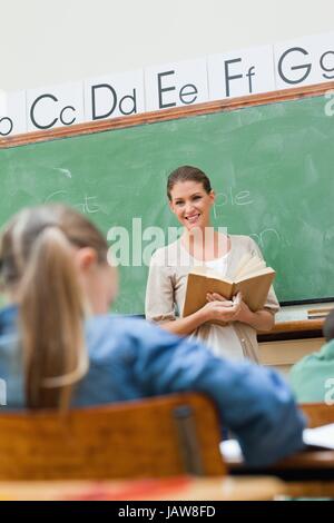 Smiling teacher with livre près de bord Banque D'Images