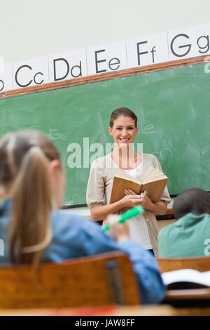 Smiling teacher holding livre près de bord Banque D'Images