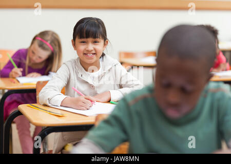 Petite fille assise à son bureau à l'école Banque D'Images