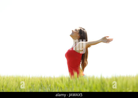 Vue latérale d'un happy girl wearing res shirt respirer l'air frais et de bras dans un champ avec un ciel blanc en arrière-plan Banque D'Images