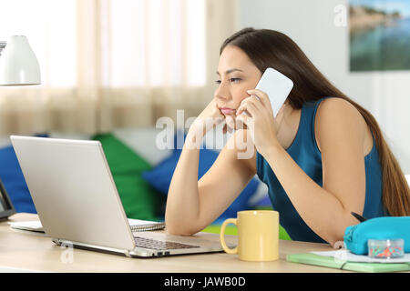 L'élève s'ennuie en attente durant un appel téléphonique dans un bureau dans sa chambre Banque D'Images