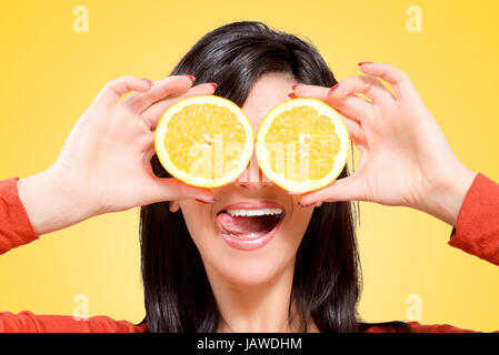 Jeune femme tenant les oranges en face de vos yeux avec un sourire joyeux et Banque D'Images