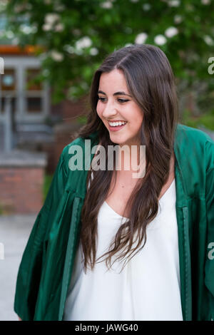 Female college student dans une lumière naturelle tout en portant son portrait mode graduation gown juste avant d'un diplômé d'une université. Banque D'Images