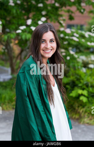 Female college student dans une lumière naturelle tout en portant son portrait mode graduation gown juste avant d'un diplômé d'une université. Banque D'Images