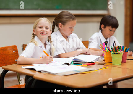 Smiling girl sitting suivant pour schoolfellows Banque D'Images