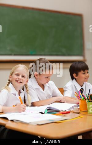 Smiling girl painting suivant pour schoolfellows Banque D'Images