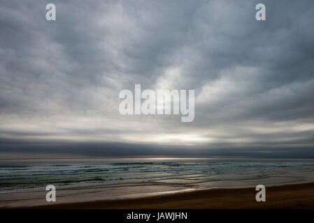 Nuages gris flottant sur une plage déserte sur un jour de tempête. Banque D'Images