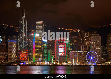 Lumière sur des gratte-ciel et de Hong Kong, roue d'observation reflétée dans le port de Victoria, Central, Hong Kong Island, Hong Kong, Chine Banque D'Images