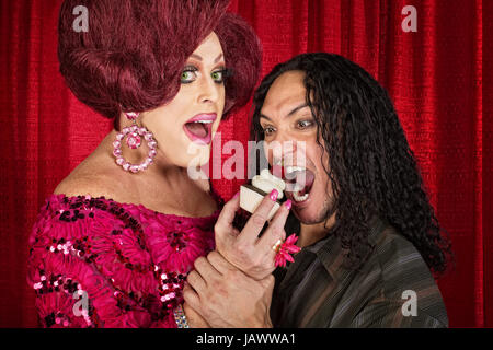 Tall drag queen et affamé man eating cupcakes Banque D'Images