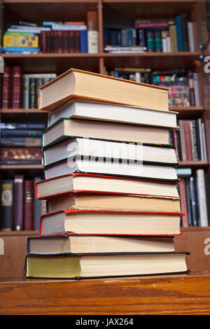 Pile de livres sur la table en bois près de bibliothèques Banque D'Images