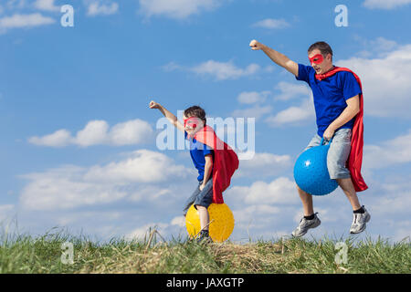 Père et fils jouer au super-héros de la journée. Les gens s'amuser en plein air.Ils sauter sur des ballons gonflables sur la pelouse. Concept de famille accueillante. Banque D'Images