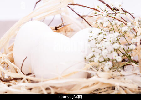 Weisse eier mit blüten im nest aus stroh ostern dekoration ostereier Banque D'Images