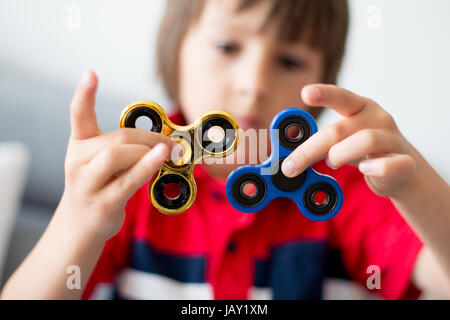 Petit enfant, garçon, jouant avec deux fidget spinner toys pour soulager le stress à la maison Banque D'Images