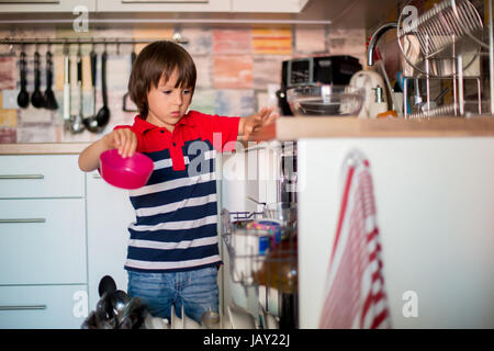 Enfant d'âge préscolaire, garçon, aider maman, mettre la vaisselle sale dans le lave-vaisselle à la maison, cuisine moderne Banque D'Images