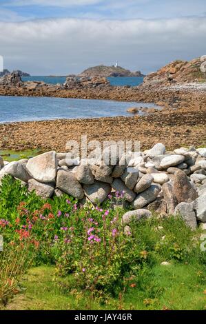 À plus d'un mur en pierre sèche vers Round Island Lighthouse, St Martin's, Penzance, Cornwall, Angleterre. Banque D'Images