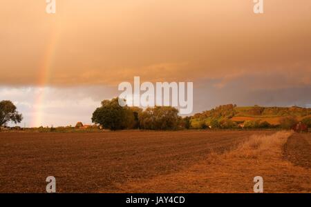 À l'égard des terres agricoles sur la colline de Meon avec un arc-en-ciel et coucher de soleil spectaculaire, Gloucestershire, Angleterre. Banque D'Images