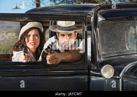 Années 1920 vintage gangsters tirant canons de fenêtre de voiture Banque D'Images