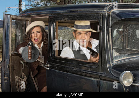 Années 1920 femme gangster tirer machine gun de voiture avec partner Banque D'Images