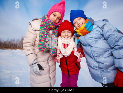 Enfants joyeux dans winterwear looking at camera tout en ayant des temps heureux à l'extérieur Banque D'Images