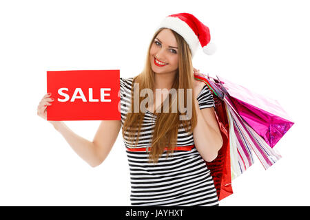 Jolie jeune femme en Santa's hat with shopping bags se dresse sur un fond blanc. Vente de Noël. Banque D'Images