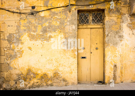 Une vieille porte sur un bâtiment en pierre dans le port de pêche de Marsaxlokk à Malte. Un détail architectural avec la peinture jaune pâle Banque D'Images